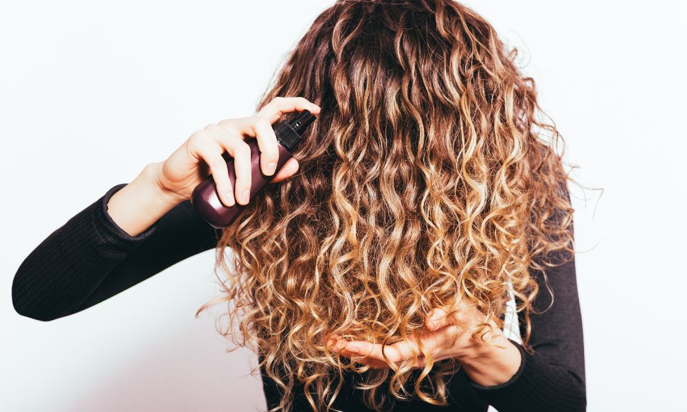 Ragazza che utilizza un prodotto cosmetico per la cura dei capelli, come quelli realizzati nello stabilimento di Biofarma Group situato a San Pietro Viminario